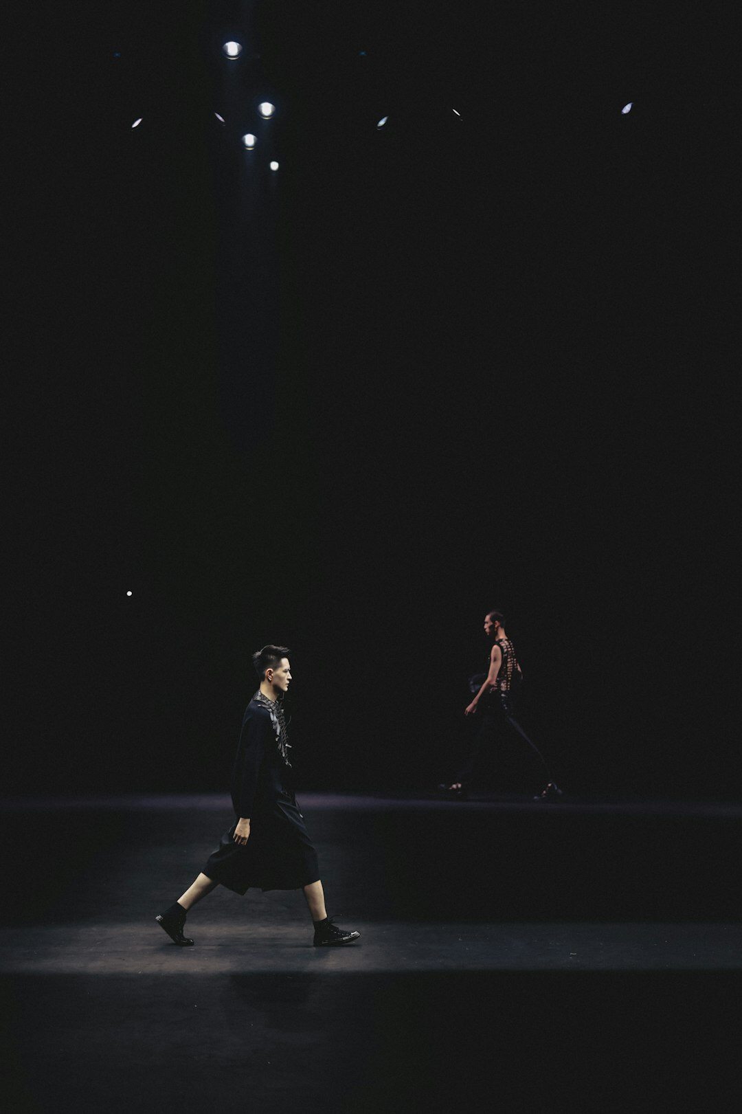 Models walking on a fashion show runway with an audience